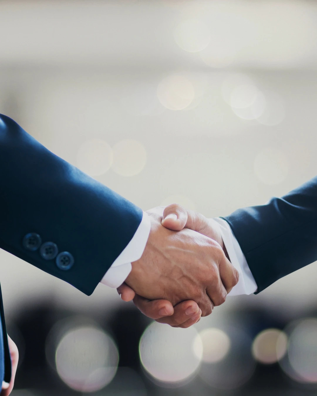 Zwei Geschäftspartner im Handschlag – symbolisiert Vertrauen, erfolgreiche Zusammenarbeit und langfristige Partnerschaften.