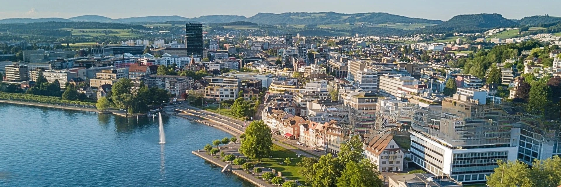 Panoramaaufnahme der Stadt Zug mit Seeufer – Standort für Avalects massgeschneiderte Dienstleistungen für Unternehmen.“